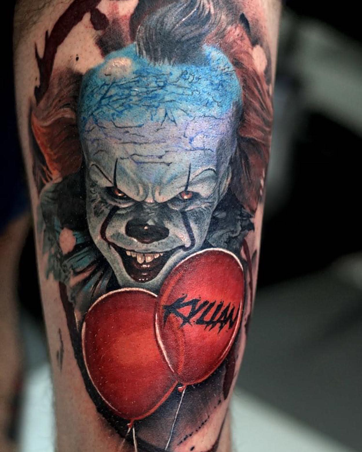 Vivid Pennywise tattoo on leg with two red balloons, one personalized with the name 'Kyllian'